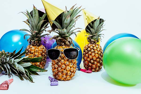 Image of a celebration: balloons and a pineapple wearing sunglasses